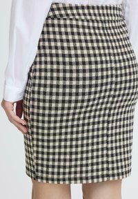 Schwarze und cremefarbene kariierte Bleistiftrock mit tailliertem Design. Verfügt über eine glatte Textur und einen Bund, der oberhalb des Knies endet.