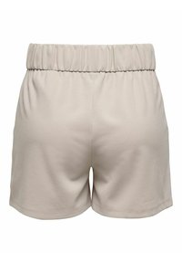 Shorts beige clair avec une taille élastique, fabriqués en tissu doux. Présentent un design simple avec une texture lisse et sans poches visibles.