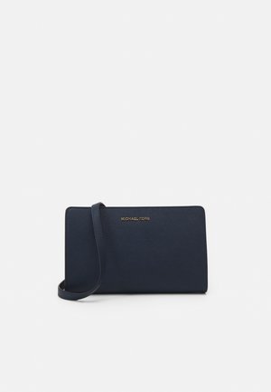 Prostokątna granatowa skórzana torba na ramię z cienkim paskiem i złotym logo Michael Kors na środku przodu.