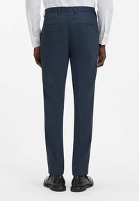 Pantaloni da uomo slim fit blu navy con motivo strutturato, due tasche posteriori, abbinati a scarpe nere e camicia bianca.