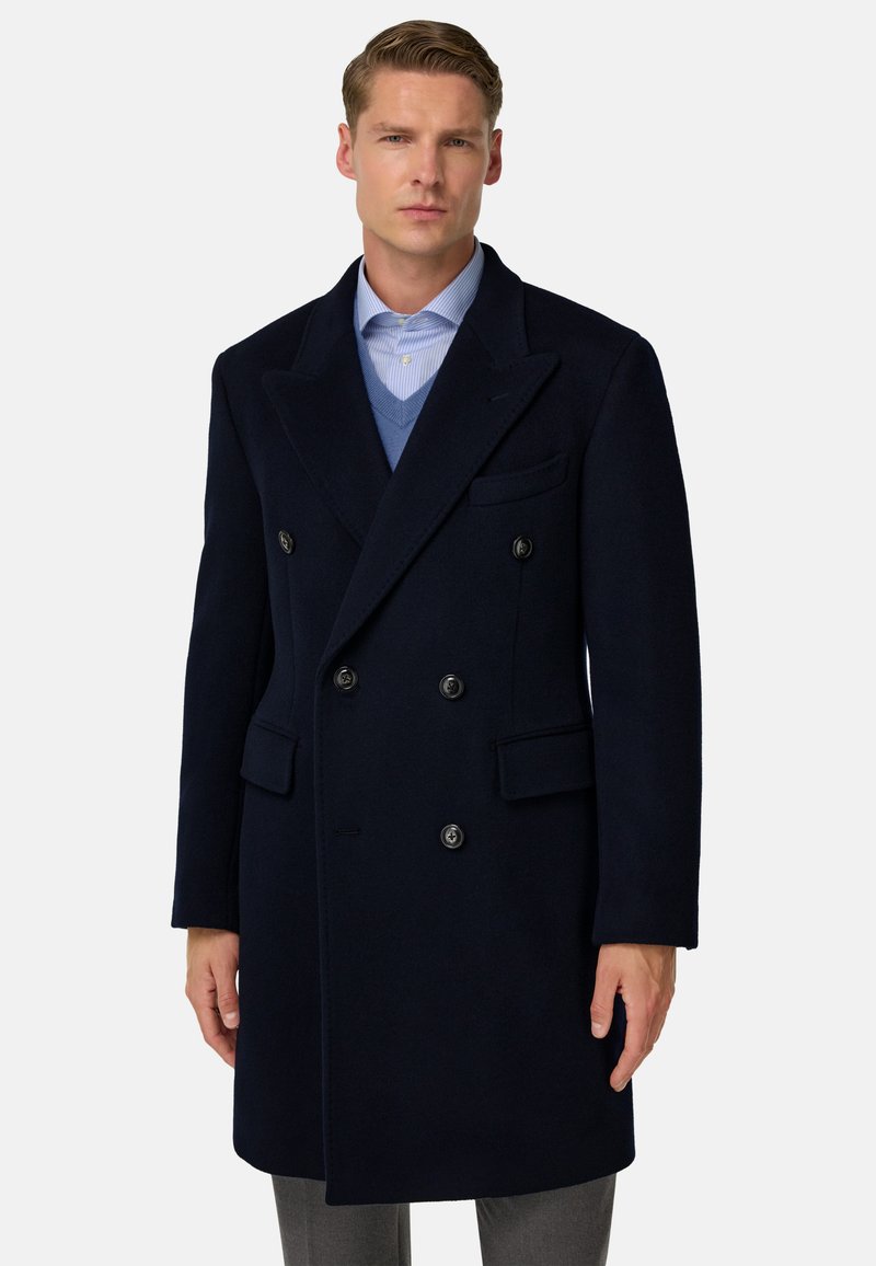 Námořnický vlněný dvouřadový kabát s klopami, dvěma předními kapsami a černými knoflíky. Přes modrý svetr a pruhovanou košili.