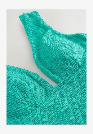 Turkis tekstureret bralette med zigzag-mønstre og tykke stropper, lavet af et blødt, elastisk materiale for komfort.