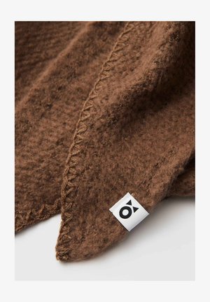 Braune Wolldecke mit einer weichen Textur, die an der Kante genäht ist und ein kleines weißes Etikett mit schwarzem Logo in der Ecke hat.