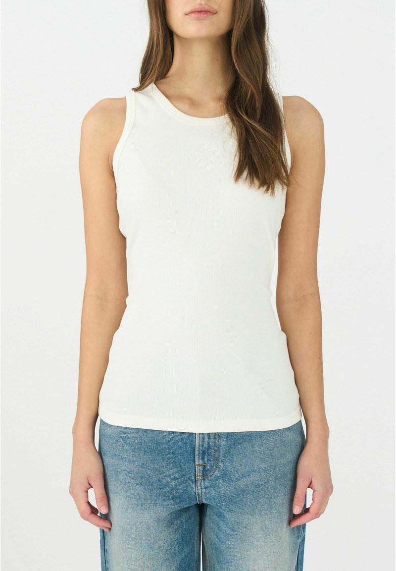 Top bianco a righe con scollatura tonda e dettaglio ricamato al centro, abbinato a jeans a gamba larga di un blu chiaro, sbiadito.