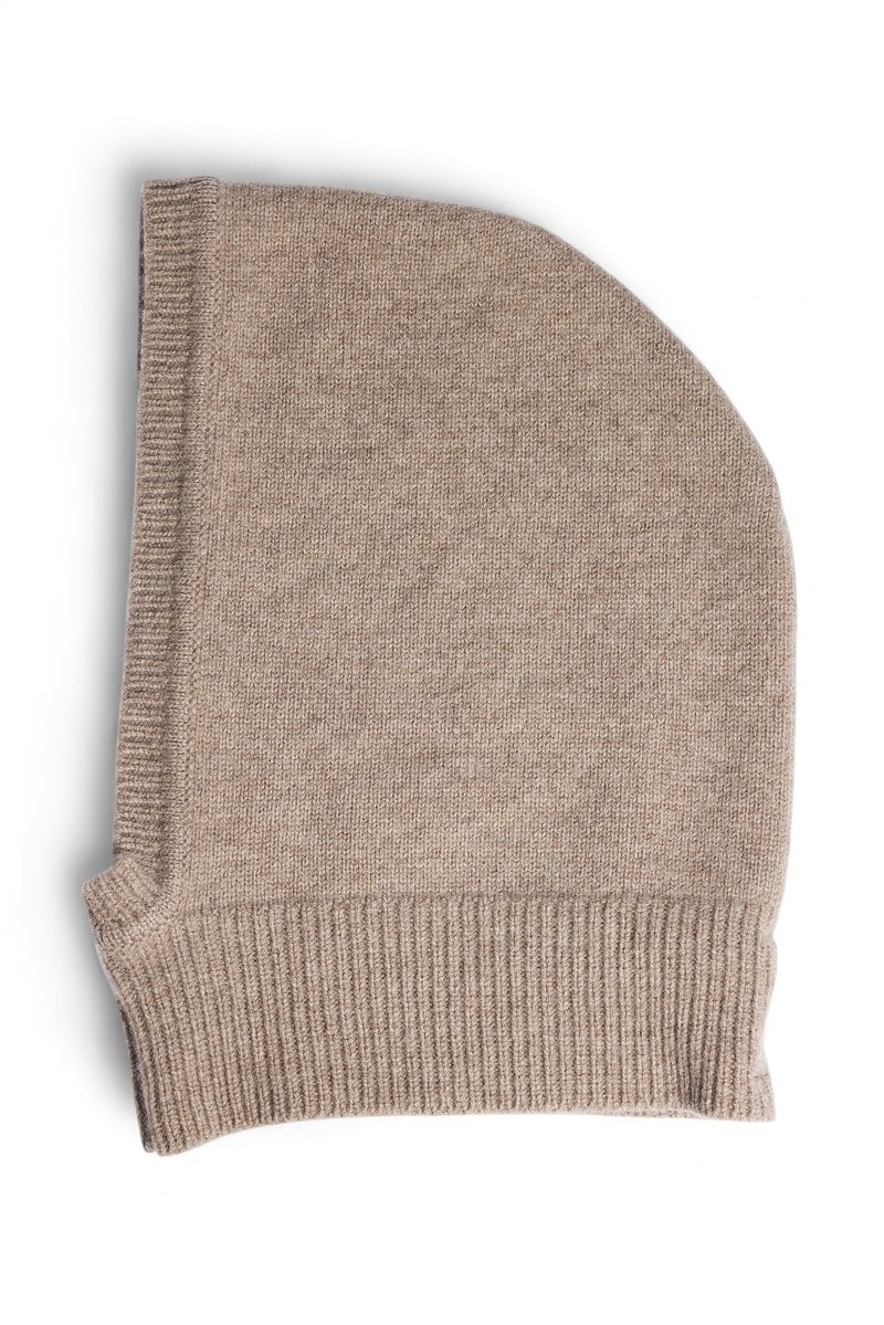 Bež pletena kapa z mehko teksturo. Ima prepognjen rob in podaljšano zasnovo, izdelana iz tople tkanine, primerne za hladnejše vreme.