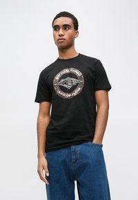 Sort bomuld T-shirt med et rundt grafikmotiv med teksten "Rip Curl Hawaii" og "Land of Aloha" i hvidt og rødt, suppleret med et logo design.