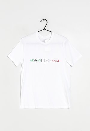 T-shirt blanc manches courtes sur un cintre noir avec le texte "Armani Exchange" en vert, noir et rouge sur la poitrine.