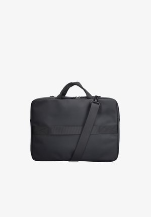 Mallette souple noire avec poignées doubles, bandoulière réglable et sangle extérieure horizontale sur fond blanc.