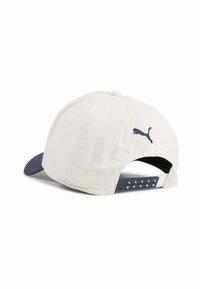 Czapka o kremowym korpusie, granatowym daszku i granatowym logo Puma. Posiada oddychającą siatkową tylnią część z diamentowymi otworami wentylacyjnymi.