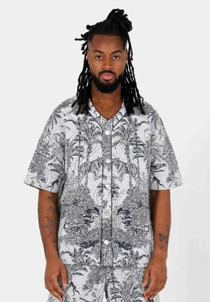Camicia a maniche corte con bottoni, caratterizzata da un motivo giungla bianco e nero con palme e tigri, realizzata in tessuto morbido e текстurizzato.