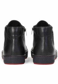 Černé kožené kotníkové boty s hladkým povrchem, se bočními zipy a kontrastní červenou stélkou, ražené logo na patě.