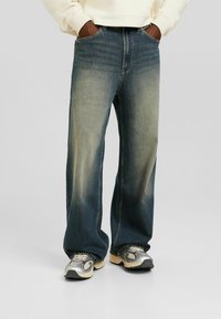 Vaaleansinisen denimin leveälahkeiset farkut, joissa on haalistunut viimeistely. Mukana klassinen viiden taskun muotoilu ja hienovaraiset tikkausdetailit.