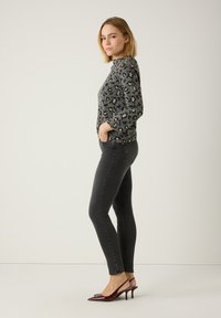 Pull en imprimé léopard gris à manches longues, associé à un jean skinny gris foncé et des escarpins en cuir verni bordeaux.