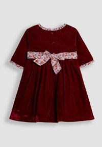 Vestido de terciopelo burdeos con un cinturón de cinta con estampado floral, mangas cortas y un escote con volantes. Cierre de botones en la parte de atrás.