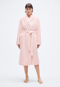 Halat de baie roz cu dungi, realizat din material pufos, având guler șal, curea și mâneci lungi cu linii orizontale texturate.