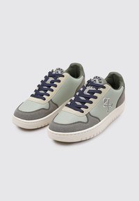 Zapatillas con parte superior de cuero verde claro, acentos de ante gris, puntera perforada, cordones azul marino y un logotipo en el lateral. Suela de goma.