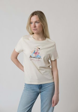 Frau mit langen blonden Haaren, die ein cremefarbenes T-Shirt mit einem pastellfarbenen Rollerbild und dem Schriftzug "Dolce Vita" sowie eine hellblaue Jeans trägt.