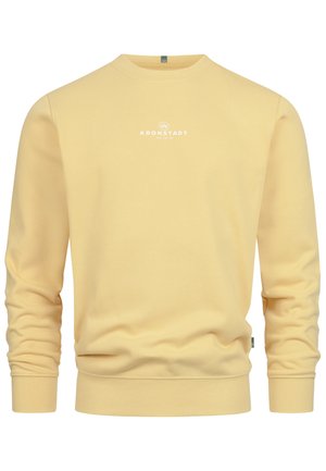 Világos sárga, pamut keverékből készült pulóver, környakú kivitelben, bordázott mandzsettákkal és a mellrészen fehér "Kronstadt" logóval.