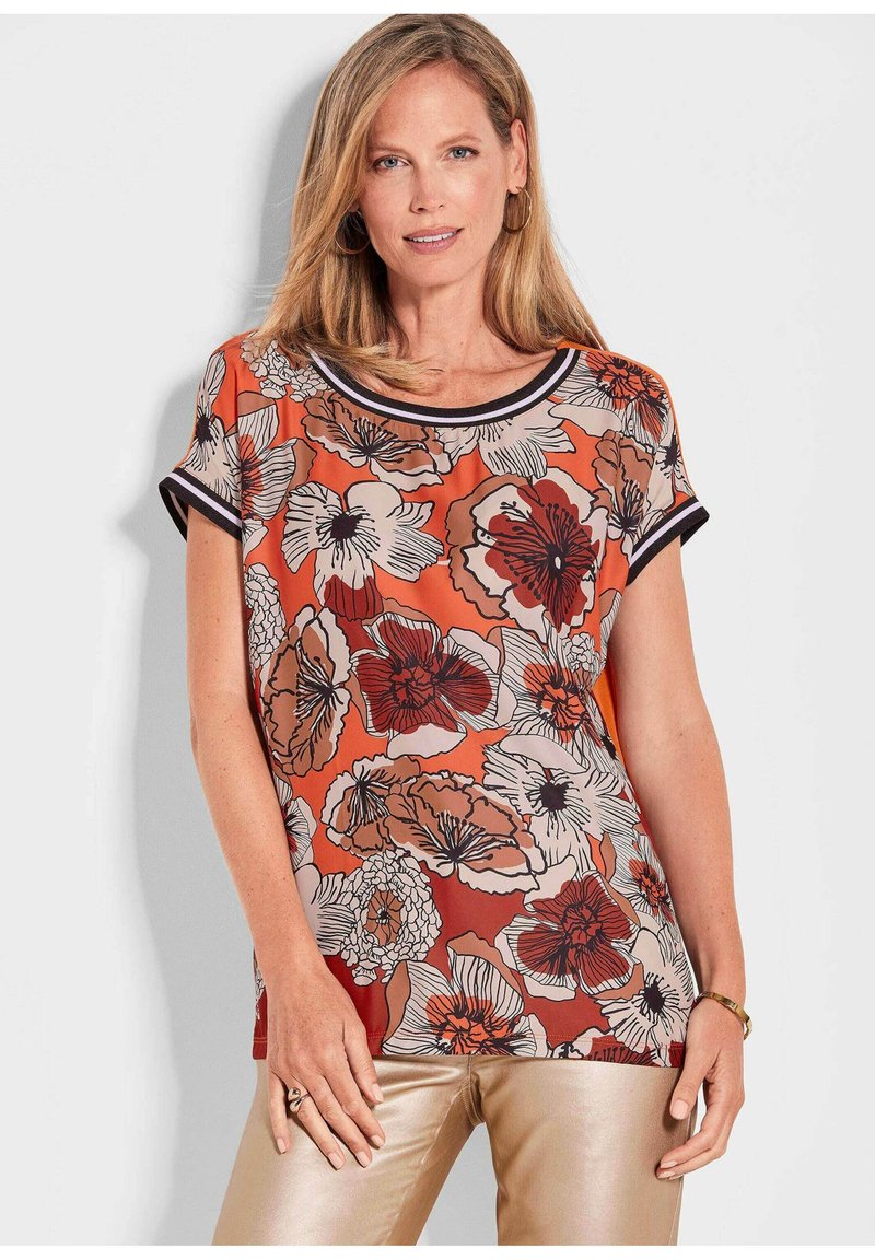 Bluse mit floralem Muster in Orange und Beige. Glattes Material mit kurzen Ärmeln und einem runden Ausschnitt, eingefasst mit schwarzem Rand.