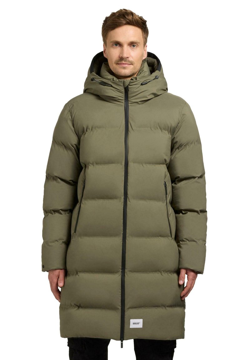 Lang olivengrøn pufferfrakke med hætte, der har lynlås foran, vandret quiltede sektioner og sidelommer, lavet af et glat materiale.