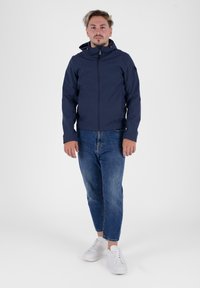 Marineblaue Kapuzenjacke mit einem Reißverschluss vorne, kombiniert mit hellblauen Jeans und weißen Sneakers. Der Stoff wirkt glatt und leicht.