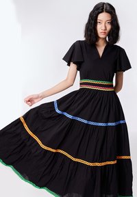 Robe noire avec des manches courtes à volants, décolleté en V, design en couches, ornée de motifs en zigzag colorés en bleu, vert, orange et rouge.