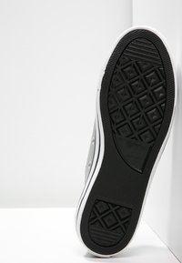 Graue Leinensneaker mit einer Gummisohle, die ein Rautenmuster aufweist, weißer Zwischensohle und schwarzer Akzentuierung an der Unterseite.