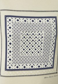Geweven textiel met een marineblauw geometrisch ontwerp op een licht crèmekleurige achtergrond. Inclusief een gestikte rand met een handgeschreven tekstdetail.