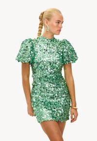 Vestido verde de lentejuelas con mangas abullonadas, cintura ajustada y un cuello alto. Textura suave y superficie brillante creada por lentejuelas redondas.