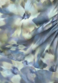 Zacht stof met een vervaagd bloemenpatroon in gedempte blauwe, grijze en crèmekleuren, met zachte plooien en een zijden textuur.