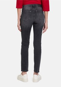 Černé skinny džíny z denimu s hladkou texturou, pěti kapsami a metalickými akcenty, doplněné o bílé tenisky.