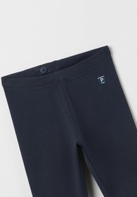 Tummansininen legginsit, jotka on valmistettu pehmeästä, joustavasta kankaasta. Vyötäröllä on nappi ja pienessä sinisessä tarrassa on 'P' logo.