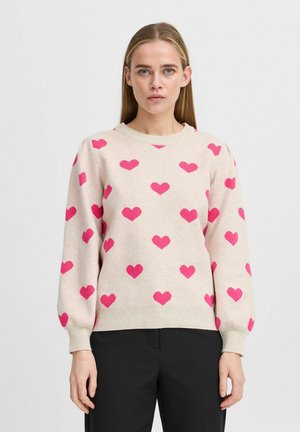 Beige striktrøje med rund hals, mønstret med pink hjerter. Har ribbede manchetter og afslutning, lavet af et blødt, tekstureret stof.
