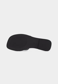 Semelle noire d'une chaussure pour femme avec un bout carré et une texture antidérapante sur un fond gris clair, taille marquée 37.