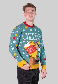 Gestickter Pullover in Teal mit roten Akzenten, der eine große Elchgrafik zeigt, der ein Getränk hält, umgeben von Sternen und Herzen. Gemütliche Textur.