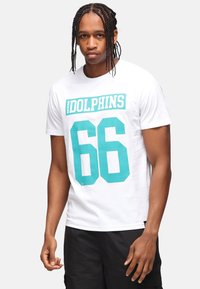 Camiseta blanca de algodón con un gráfico en color teal que dice "MIAMI DOLPHINS" y "66" en grandes números. Diseño de mangas cortas y cuello redondo.