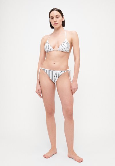 Baltas bikini komplektas su trikampio formos viršumi ir šoninėmis rišamosiomis kelnaitėmis, papuoštas ryškiais juodais užrašais. Lygus audinys, minimalistiškas dizainas.