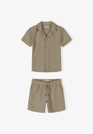 Cămașă bej cu mâneci scurte, nasturi și guler, asortată cu pantaloni scurți cu șnur, dintr-un material ușor și texturat.