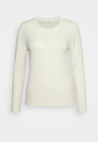 Langermet, elfenben ribbet skjorte med rund hals. Myk tekstur, tettsittende design og subtile kantdetaljer. Passer for lagdeling.
