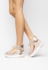 Lightweight wedge sandals in beige with mesh fabric panels, metallic accents, and a textured animal print detail on the heel.