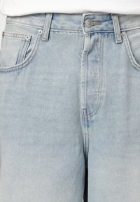 Lys blå denim jeans med høj talje, fem-lomme design og kontrastsyet. Har en knaplukning og metalbeslag.