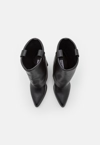 Czarne skórzane botki ze spiczastymi noskami, gładką fakturą, składanym wykończeniem i pętlami na obcasie dla łatwiejszego zakładania.