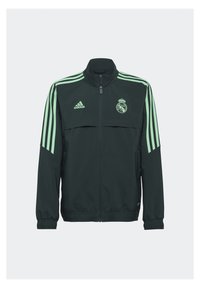 Chaqueta verde con cremallera y cuello alto, tres franjas verticales en cada manga y un distintivo en el pecho. Fabricada con un tejido suave y elástico.