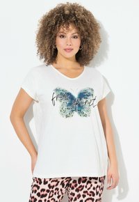 Camiseta de algodón blanca con un gráfico de mariposa azul y el texto "espíritu libre". Manga corta, corte relajado, textura suave.