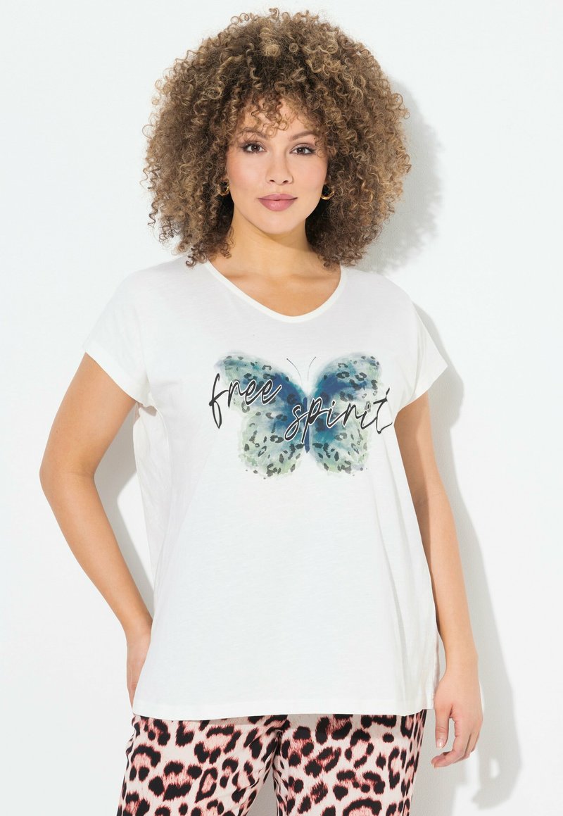 Camiseta de algodón blanca con un gráfico de mariposa azul y el texto "espíritu libre". Manga corta, corte relajado, textura suave.