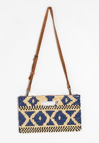 Bolso de cuentas con patrones geométricos en azul marino, crema y negro; cuenta con un asa superior y una correa de cuero marrón desmontable.