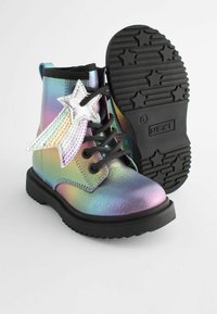Metallic regnbue ankelstøvler med en sort gummisål, der har en sølvstjerne og flerfarvede striber på siden. Sorte snørebånd medfølger.