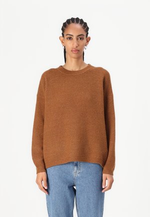 Brown striped knit sweater with a round neckline and dropped shoulders, paired with light blue jeans. Soft texture and relaxed fit.