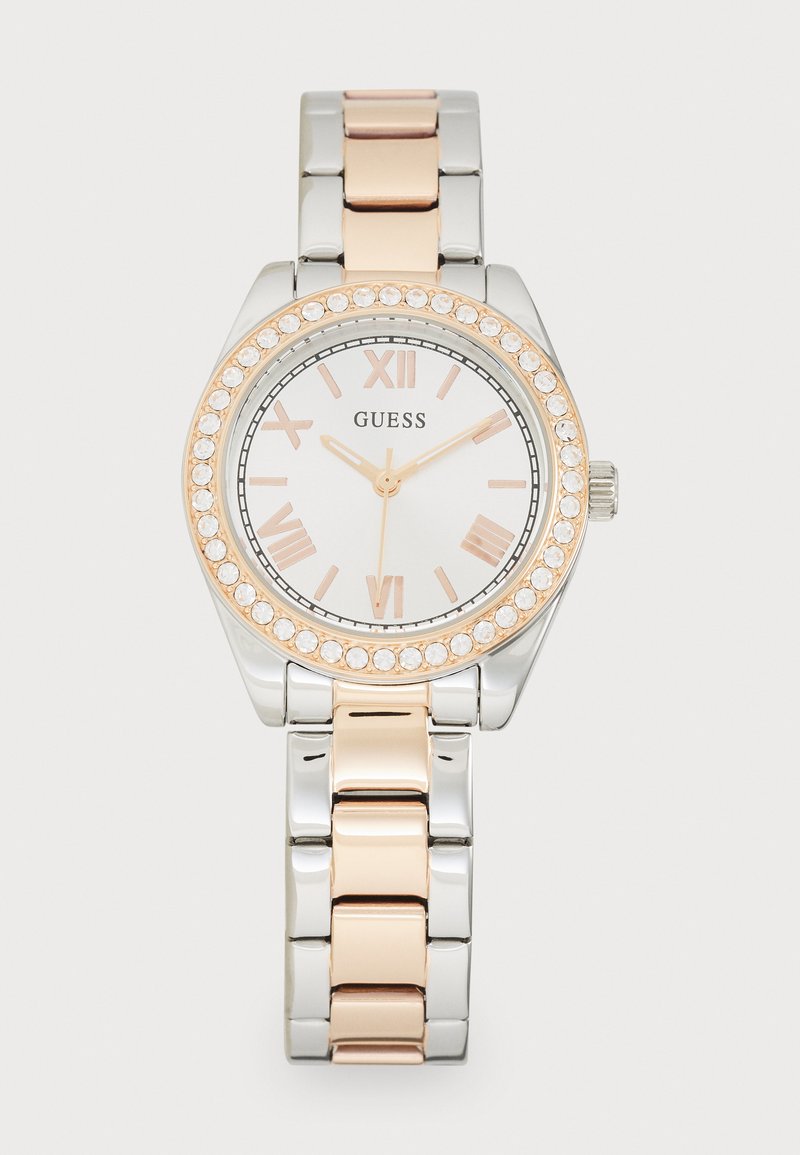 Guess watch with a silver and rose gold metal band, circular white face, Roman numerals, and crystal-accented bezel.