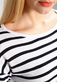 Top in cotone a righe bianche e blu navy con scollo ampio, texture morbida e maniche corte. Presenta righe orizzontali di larghezza variabile.